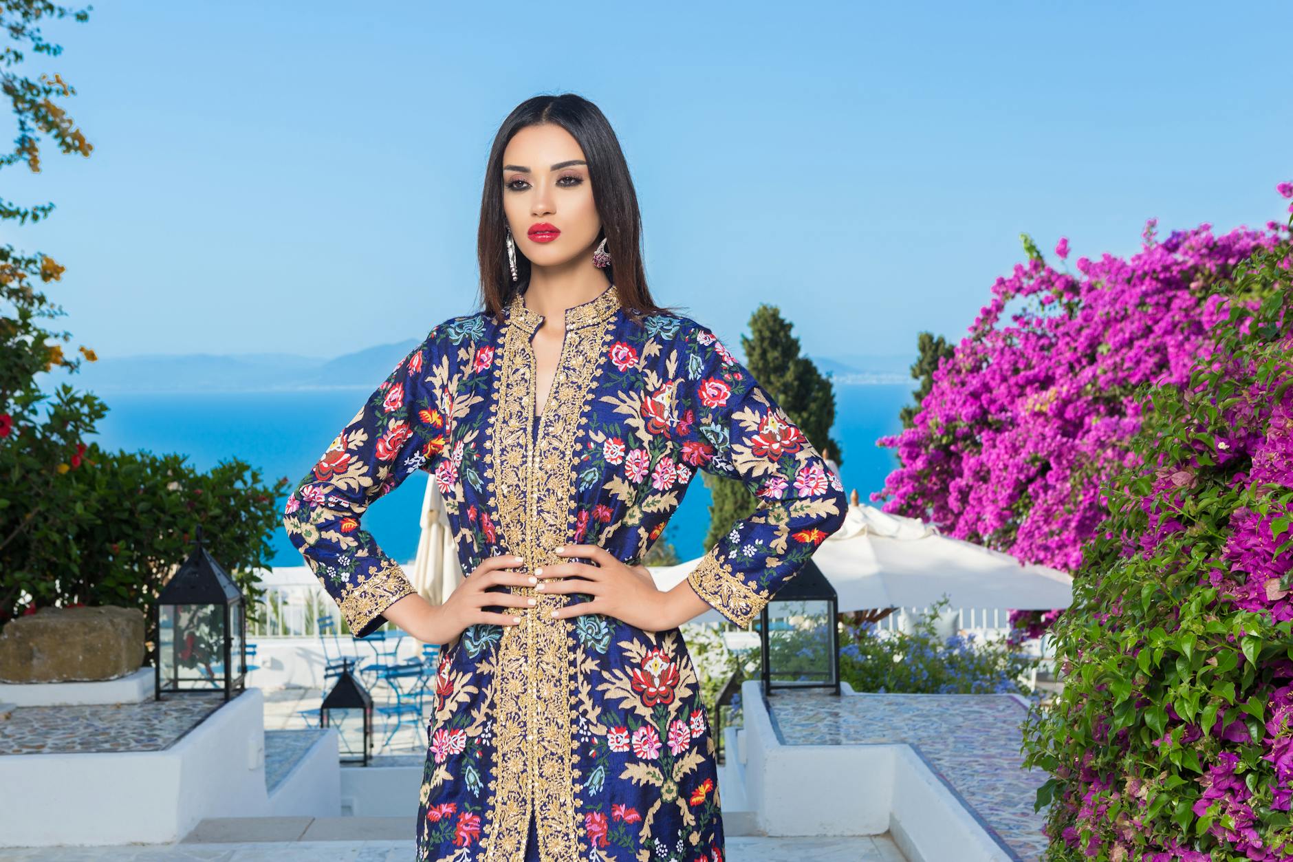 a woman in blue floral long sleeve dress standing near purple flower